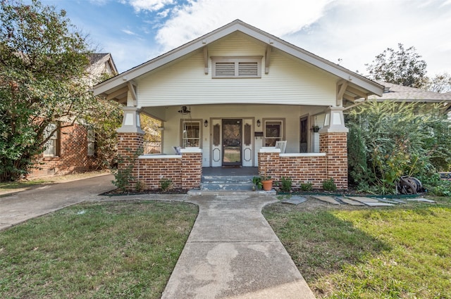 bungalow with covered porch and a front lawn