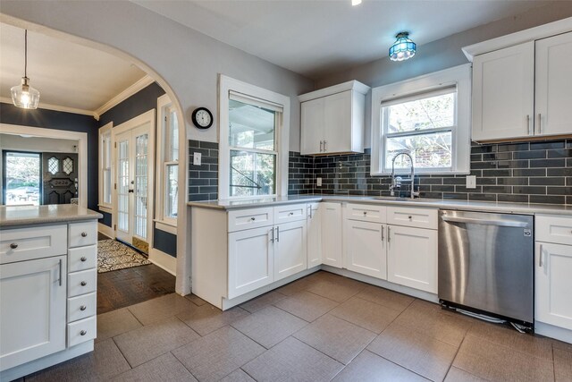 kitchen with hanging light fixtures, white cabinets, stainless steel dishwasher, and a wealth of natural light