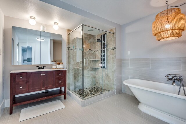 bathroom with tile patterned flooring, vanity, tile walls, and plus walk in shower