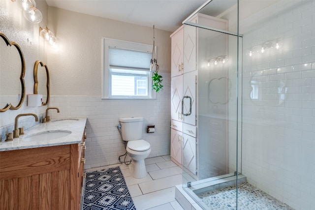 bathroom with tile patterned flooring, an enclosed shower, toilet, vanity, and tile walls