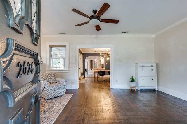 sitting room with ceiling fan with notable chandelier, crown molding, and dark wood-type flooring