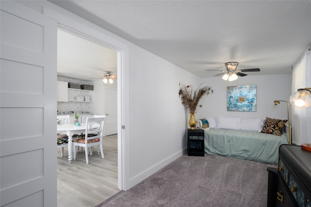 bedroom featuring ceiling fan, light hardwood / wood-style flooring, and a textured ceiling