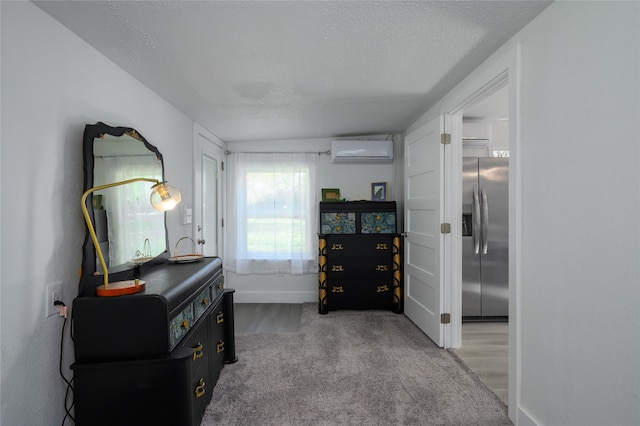 hallway with a wall mounted air conditioner, wood-type flooring, and a textured ceiling