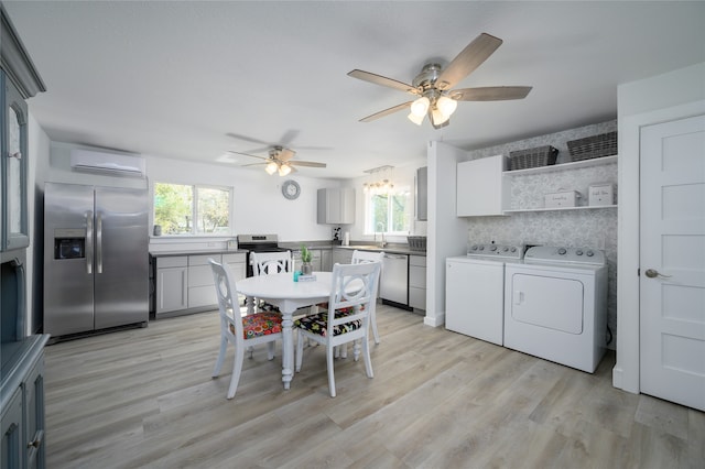 dining area with a wall mounted air conditioner, plenty of natural light, washing machine and dryer, and light wood-type flooring