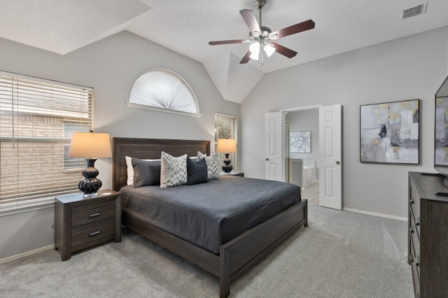 bedroom featuring light colored carpet, ensuite bath, vaulted ceiling, and a textured ceiling