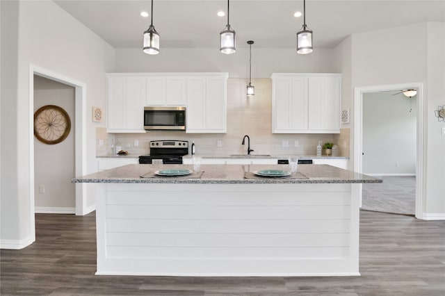 kitchen with white cabinetry, a center island with sink, decorative light fixtures, and appliances with stainless steel finishes