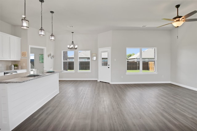 kitchen with dark hardwood / wood-style flooring, ceiling fan with notable chandelier, stone countertops, white cabinetry, and hanging light fixtures