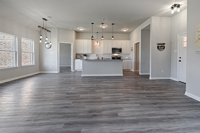 kitchen featuring a center island with sink, white cabinetry, hanging light fixtures, and appliances with stainless steel finishes