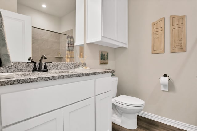 bathroom with hardwood / wood-style floors, vanity, toilet, and walk in shower