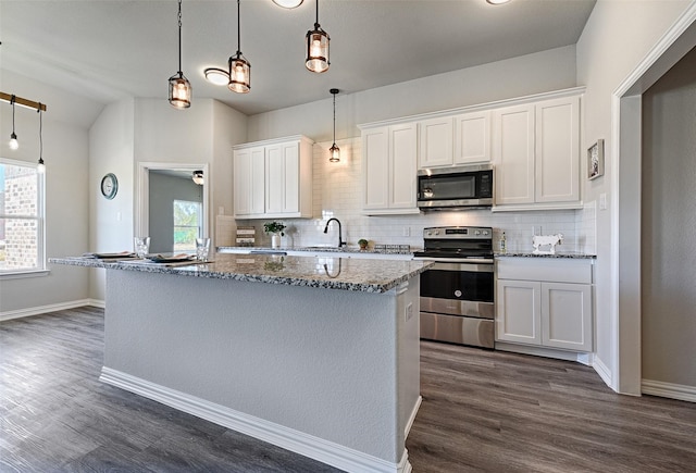 kitchen featuring white cabinetry, a center island, hanging light fixtures, dark stone countertops, and stainless steel appliances