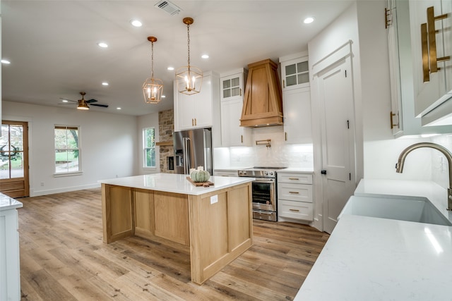 kitchen featuring sink, white cabinets, light hardwood / wood-style flooring, a kitchen island, and appliances with stainless steel finishes