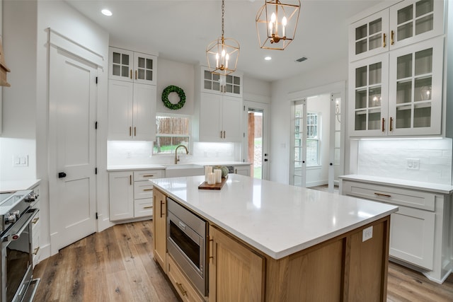 kitchen featuring a center island, white cabinetry, appliances with stainless steel finishes, and light hardwood / wood-style flooring