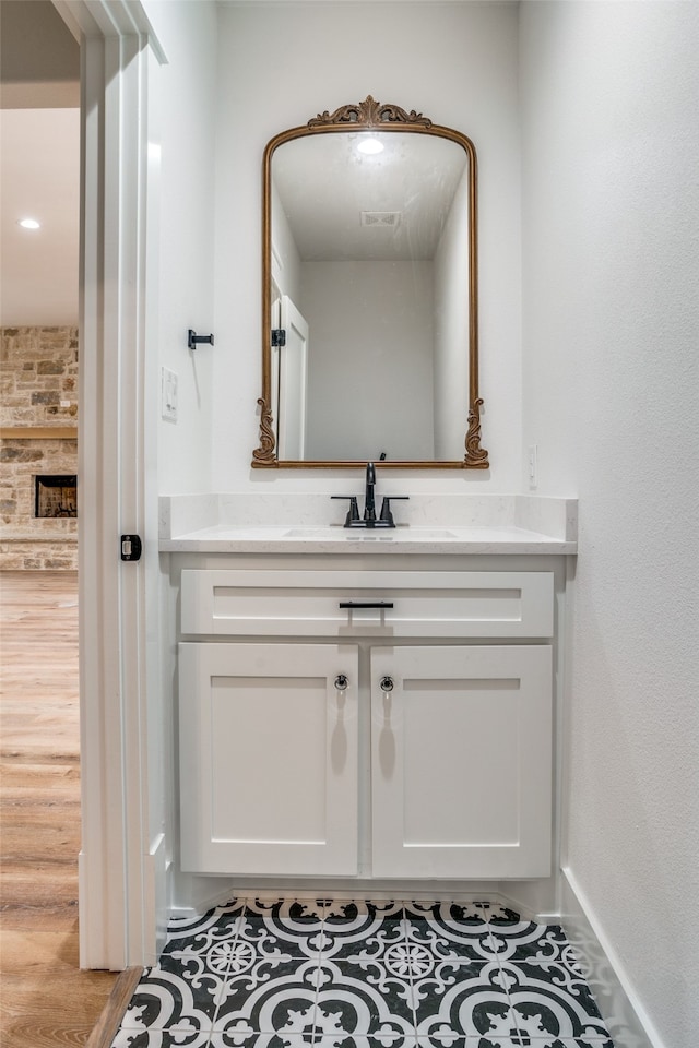 bathroom with hardwood / wood-style flooring, vanity, and a fireplace