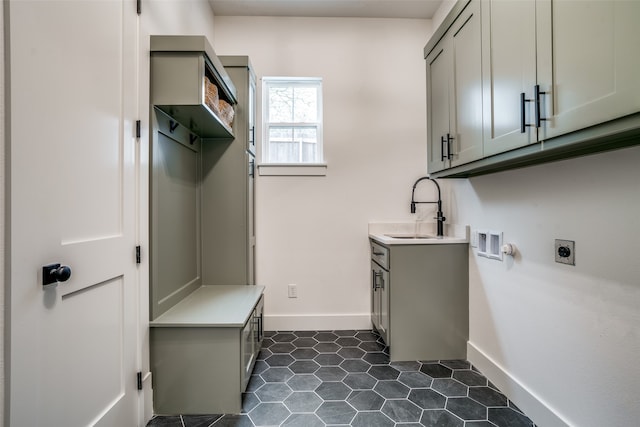 clothes washing area with sink, washer hookup, cabinets, hookup for an electric dryer, and dark tile patterned flooring