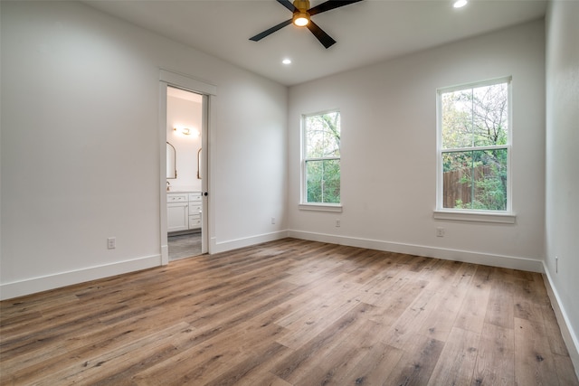 unfurnished bedroom with connected bathroom, ceiling fan, light hardwood / wood-style flooring, and multiple windows