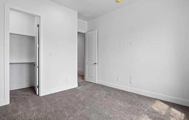 unfurnished bedroom with a closet and dark colored carpet