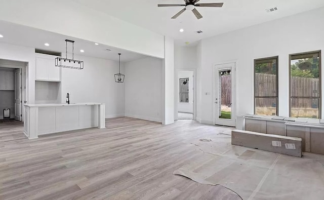 unfurnished living room with a wealth of natural light, sink, ceiling fan, and light hardwood / wood-style floors