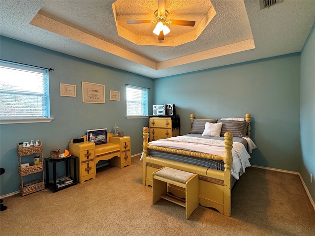 bedroom with a raised ceiling, ceiling fan, and light colored carpet