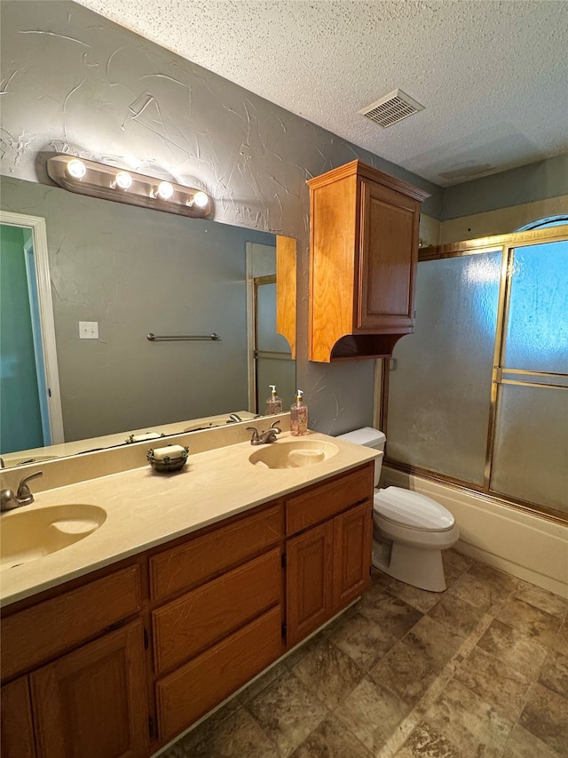 full bathroom with shower / bath combination with glass door, vanity, a textured ceiling, and toilet