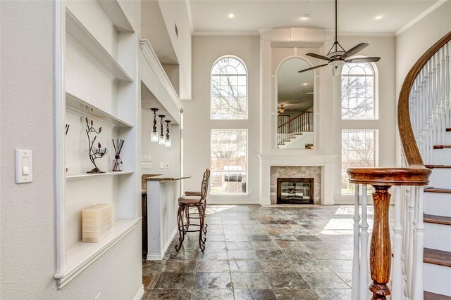 unfurnished living room featuring ceiling fan, plenty of natural light, and a high ceiling