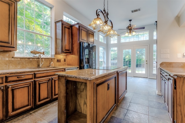 kitchen with pendant lighting, black appliances, sink, decorative backsplash, and a kitchen island