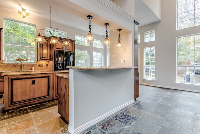 kitchen featuring light stone countertops, black fridge with ice dispenser, a wealth of natural light, and sink