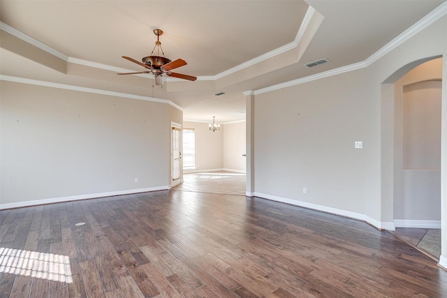 unfurnished room featuring ceiling fan with notable chandelier, ornamental molding, dark wood-type flooring, and a tray ceiling