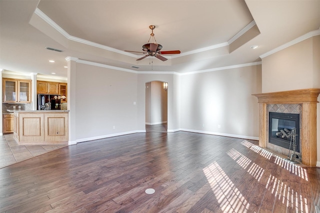 unfurnished living room featuring light hardwood / wood-style flooring, a raised ceiling, ceiling fan, and crown molding