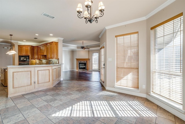 kitchen featuring backsplash, ceiling fan with notable chandelier, crown molding, hanging light fixtures, and black microwave