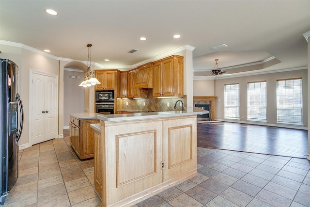 kitchen with kitchen peninsula, crown molding, black appliances, and decorative light fixtures