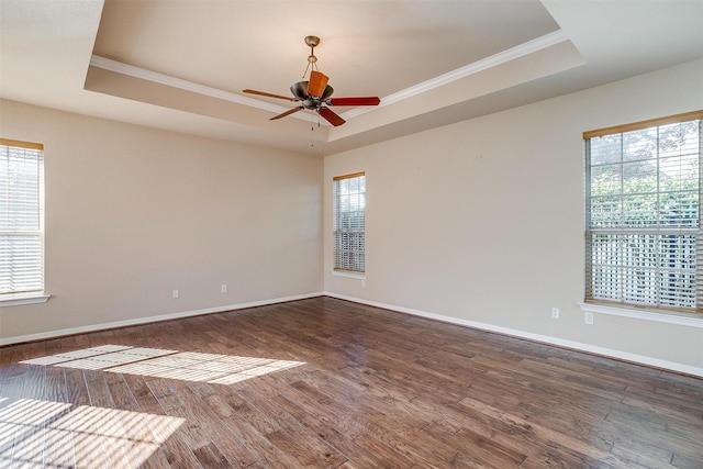 spare room featuring a tray ceiling, ceiling fan, dark wood-type flooring, and ornamental molding