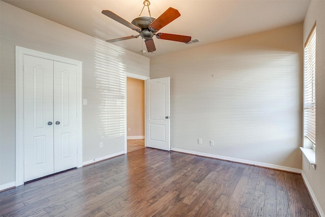 unfurnished bedroom featuring a closet, dark hardwood / wood-style floors, and ceiling fan