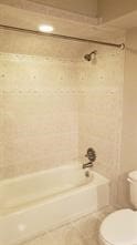 bathroom with tile patterned flooring, tiled shower / bath, and toilet