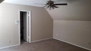 additional living space featuring dark colored carpet, ceiling fan, and vaulted ceiling