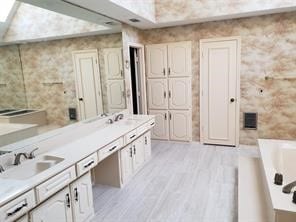 bathroom with a tub, vanity, a skylight, and hardwood / wood-style flooring