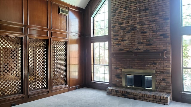 unfurnished living room with light colored carpet, a fireplace, and a high ceiling