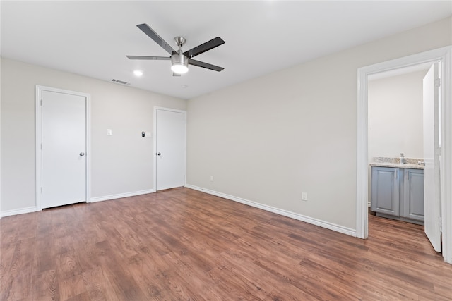 unfurnished bedroom featuring connected bathroom, dark hardwood / wood-style floors, and ceiling fan