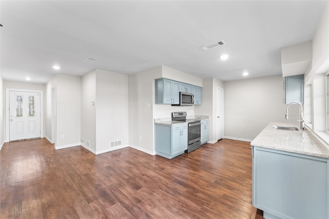 kitchen with light stone countertops, sink, appliances with stainless steel finishes, and dark wood-type flooring