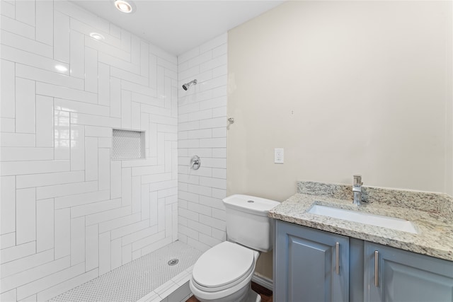 bathroom featuring tiled shower, vanity, and toilet