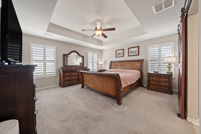 carpeted bedroom featuring a tray ceiling, multiple windows, and ceiling fan