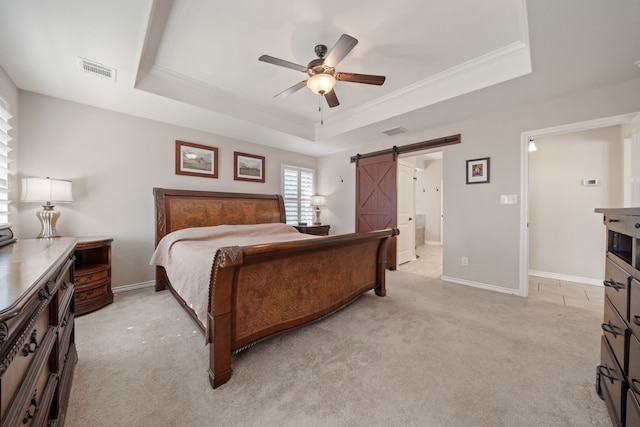 carpeted bedroom with a barn door, a raised ceiling, ceiling fan, and ornamental molding