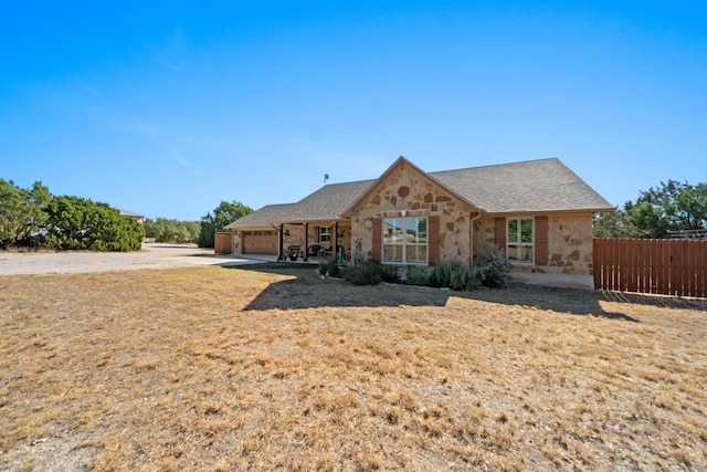 view of front of home with stone siding, fence, and an attached garage