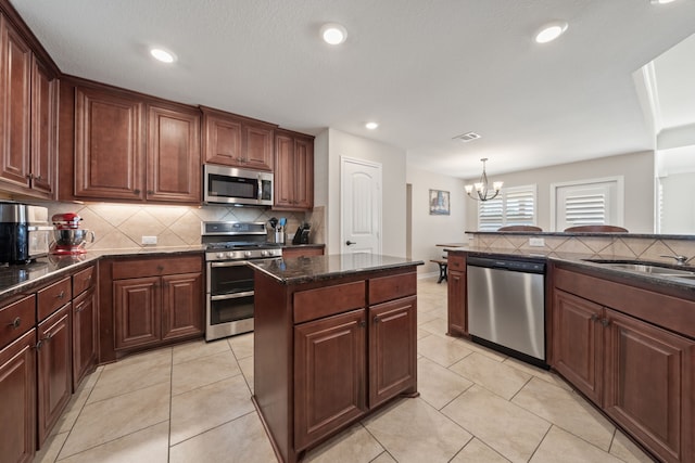 kitchen with a center island, an inviting chandelier, sink, decorative light fixtures, and stainless steel appliances