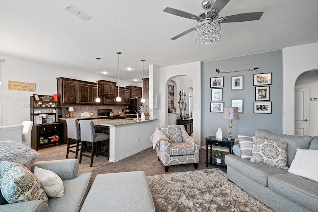 living room featuring ceiling fan, sink, and light carpet