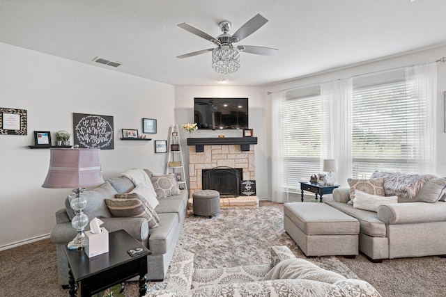 living room featuring ceiling fan, a stone fireplace, and carpet floors