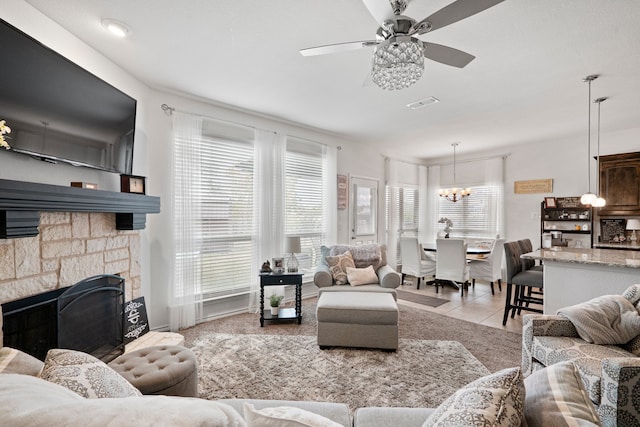 tiled living room featuring ceiling fan with notable chandelier and a fireplace