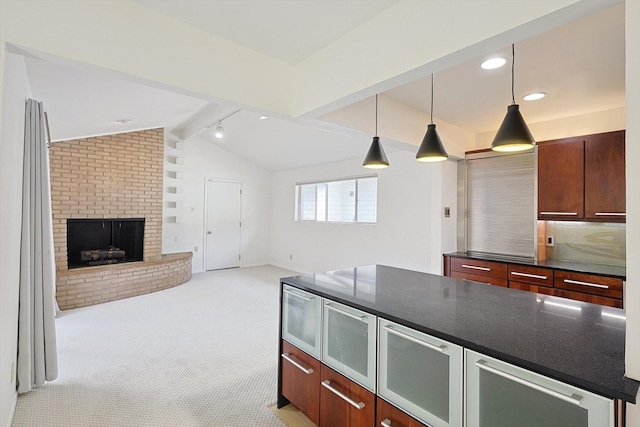 kitchen featuring vaulted ceiling with beams, decorative light fixtures, light carpet, dark stone countertops, and a fireplace