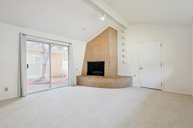 unfurnished living room with light colored carpet, track lighting, lofted ceiling with beams, and a brick fireplace