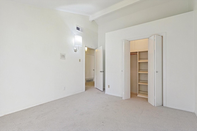 unfurnished bedroom with light colored carpet, lofted ceiling with beams, a closet, and a walk in closet