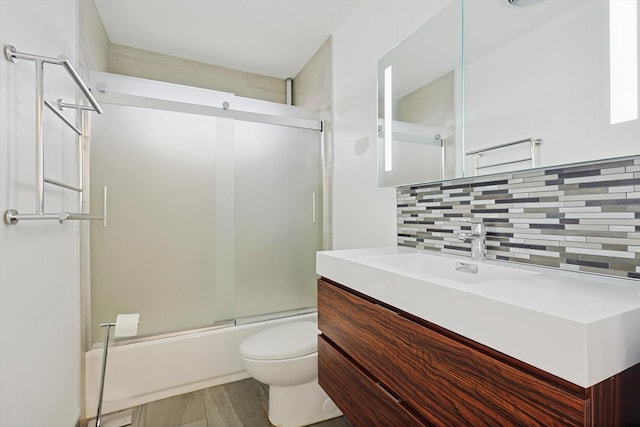 full bathroom with tasteful backsplash, bath / shower combo with glass door, vanity, and toilet